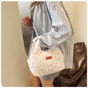 Detail view of the floral canvas lunch bag showing the brand leather patch and side pocket