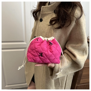 Detail of rose red quilted bucket bag featuring black bow embroidery and drawstring closure