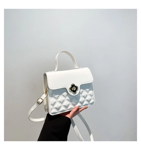 Detail of white quilted crossbody bag with a black and gold clover leaf metal clasp