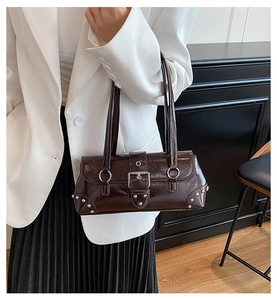Close-up of a vintage brown baguette bag with silver studs and twin shoulder straps