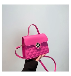 Detail of rose pink quilted crossbody bag featuring a golden floral twist lock and handle
