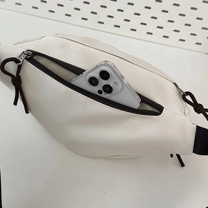 Detail shot of off-white crossbody bag showing capacity with a smartphone inside