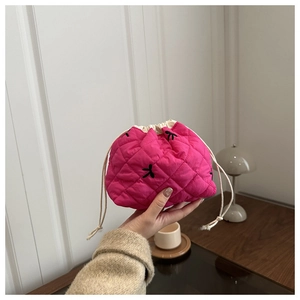 Close-up of pink quilted drawstring bucket bag with black bow embroidery detail