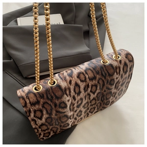 Détail du sac léopard avec chaîne dorée posé sur une veste de costume grise