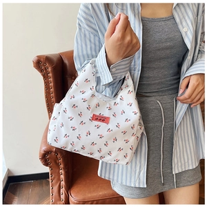 Close-up of the floral canvas handbag with a red brand label worn on the arm