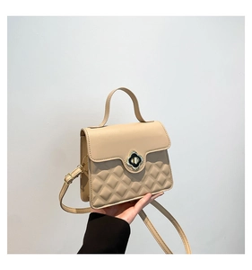Close-up of beige handbag featuring diamond quilted pattern and clover-shaped golden lock