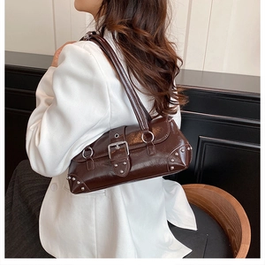 Detail view of glossy dark brown leather shoulder bag with silver buckle and metal rivets