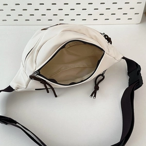 Detailed view of white canvas fanny pack interior with brown strap and plastic buckle