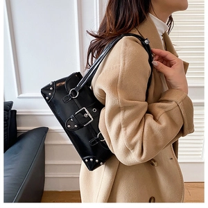 Close-up of a black glossy leather underarm bag with silver rivets and buckle detail