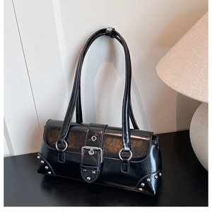Detailed close-up of vintage black glossy shoulder bag with metal buckle and rivets