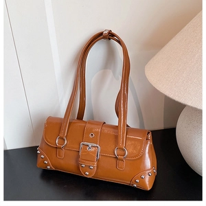 Close-up of vintage brown baguette bag with glossy texture and silver rivet details
