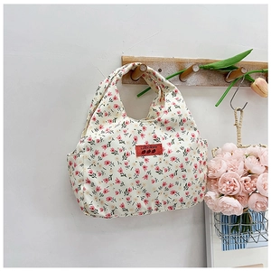 Detailed view of cream floral canvas lunch bag hanging with tulip pattern and red label