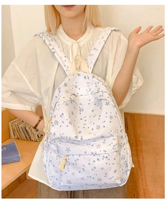 Detail view of a white canvas backpack featuring blue star patterns in a campus setting