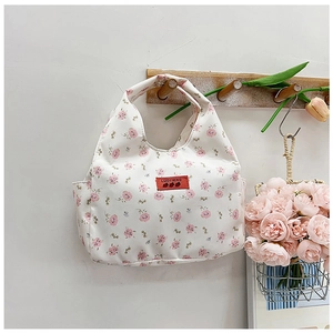 Detailed view of the small floral canvas bag with side pocket and red brand label