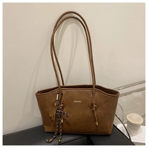 Detail of a brown retro tote bag featuring fine straps and a metal tennis racket charm