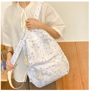 Detail view of the white canvas backpack with blue star patterns and adjustable straps