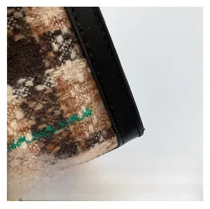 Détail du tissu en laine à carreaux marron et bordure en cuir noir avec coutures fines