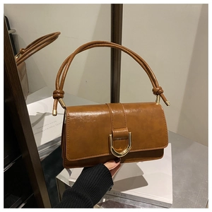 Détail d'un sac bandoulière marron en similicuir avec boucle en U dorée et bandoulière nouée