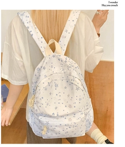 Back view of a white student backpack with blue star patterns and knotted zippers