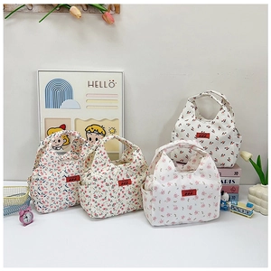 Detail of four floral canvas lunch bags with side pockets in a lifestyle desk setting