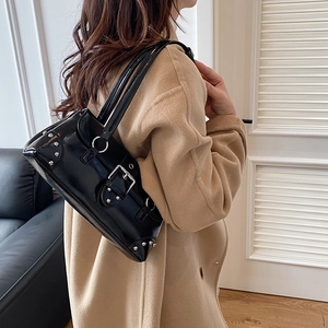 Vintage black patent leather shoulder bag with silver buckles shown on female model