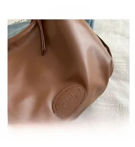 Detailed macro view of brown leather texture and embossed fashion brand lettering on bag