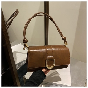 Détail d'un sac à main marron avec boucle dorée en U et détails de bandoulière nouée