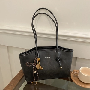 Large black matte faux leather tote bag with long straps and gold tennis racket charm