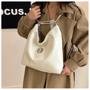 Détail du sac cabas blanc avec texture froissée brillante et logo M en métal argenté