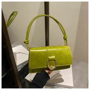 Détail du sac à main en cuir vert avec boucle en fer à cheval dorée et bandoulière nouée