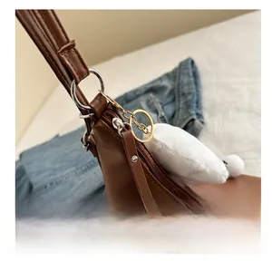 Detail of smooth metal zipper and brown faux leather texture on minimalist shoulder bag