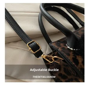 Gros plan du sac à main léopard avec boucles dorées et bandoulière noire réglable