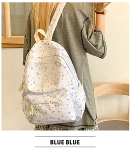 Close-up of white canvas backpack with blue star patterns and cotton rope zipper pullers