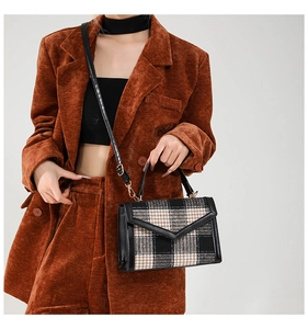 Détail du sac bandoulière vintage en laine à carreaux avec finitions en cuir noir et rabat en V