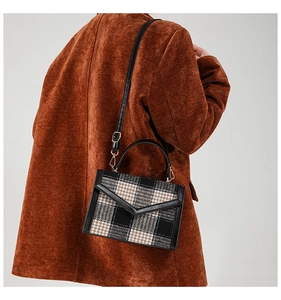 Gros plan du sac bandoulière à carreaux marron et noir porté par un mannequin femme