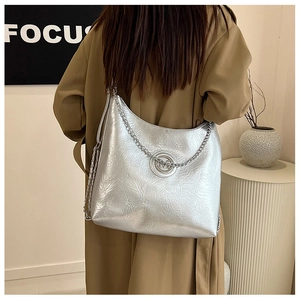 Sac fourre-tout argenté avec texture plissée et chaîne porté par un mannequin de mode