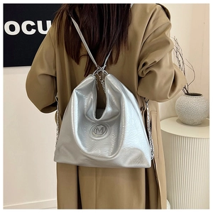 Détail d'un sac cabas argenté avec texture plissée, logo M et bandoulière en chaîne