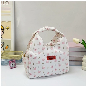 Detail of floral lunch bag with red leather brand tag and pink flower pattern on white canvas