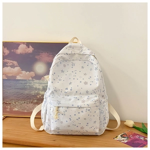 Detail of a beige star-patterned school backpack with front pocket on a wooden desk
