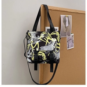 Close-up of black canvas tote with yellow graffiti patterns and adjustable shoulder straps