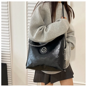 Détail du sac cabas en cuir froissé noir avec logo M et décorations de chaîne argent