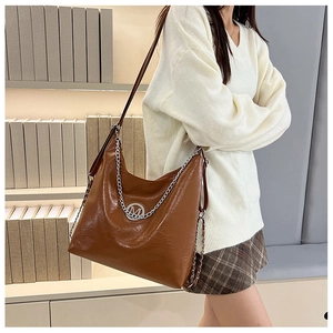 Gros plan du grand sac hobo marron avec logo M argenté et bandoulière en chaîne épaisse