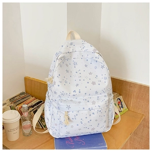 Detail shot of fresh white floral backpack with blue star patterns on a wooden shelf