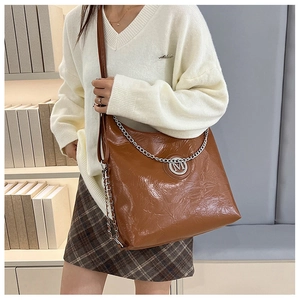 Détail du sac cabas marron avec chaîne argentée et logo M sur cuir synthétique plissé