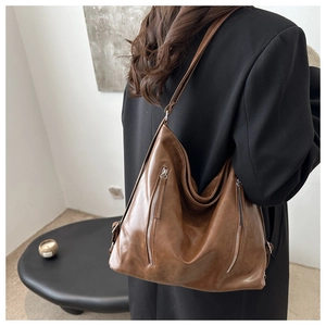 Vista dettagliata della borsa hobo marrone vintage con zip indossata dal modello