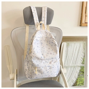 Detailed close-up of cream canvas backpack with blue star patterns and zip pocket