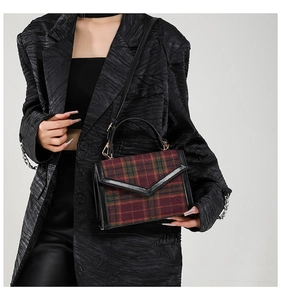 Détail du sac bandoulière tartan rouge et vert avec rabat en V et garniture en cuir noir