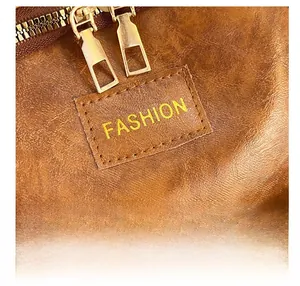 Détail du sac à dos en cuir marron avec double fermeture éclair dorée et étiquette Fashion