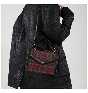 Gros plan d'un sac à main en tweed à carreaux vintage avec bordure en cuir sur un mannequin