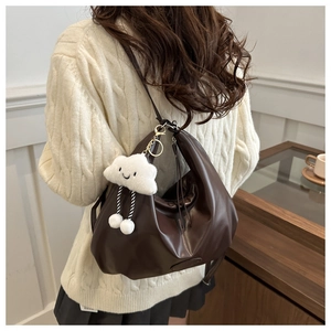 Close-up of deep brown pleated leather tote bag with a cute white plush cloud charm